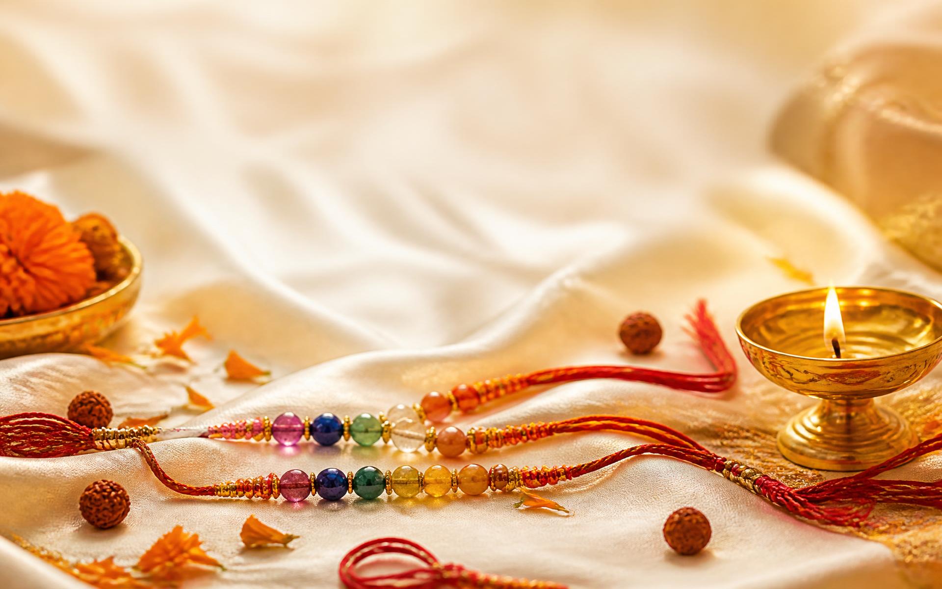 Festive Raksha Bandhan arrangement with chakra-stone rakhis, a brass diya and marigold petals on ivory silk